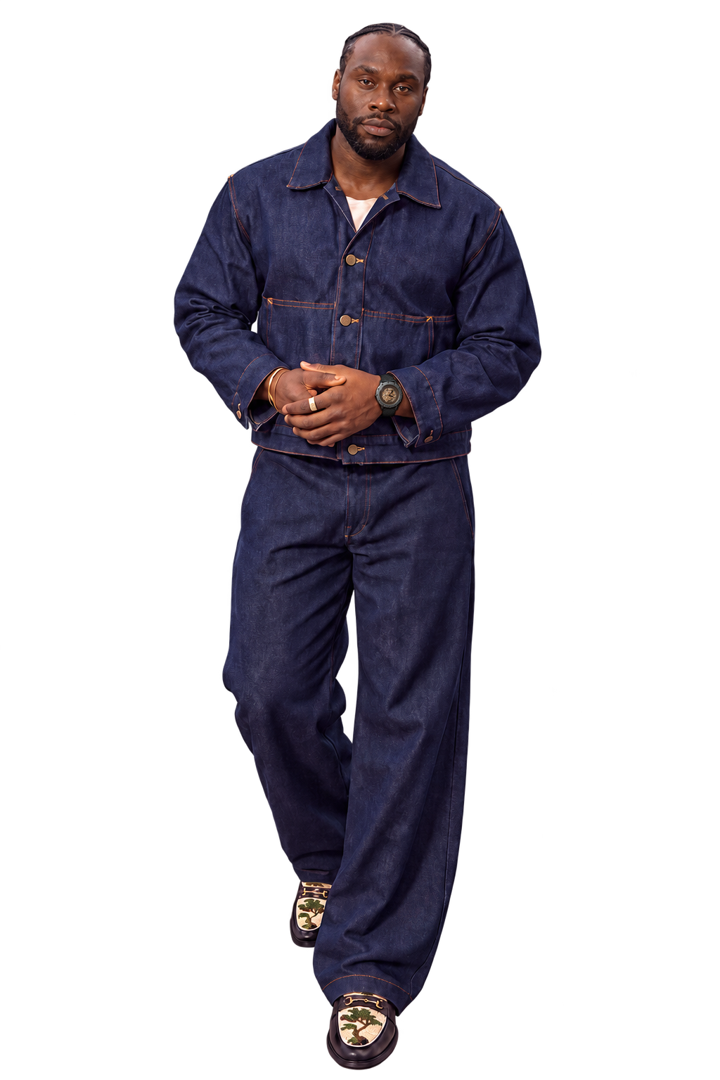 Charles Assa en pied, mains jointes, en tenue bleu indigo et mocassins à motif.